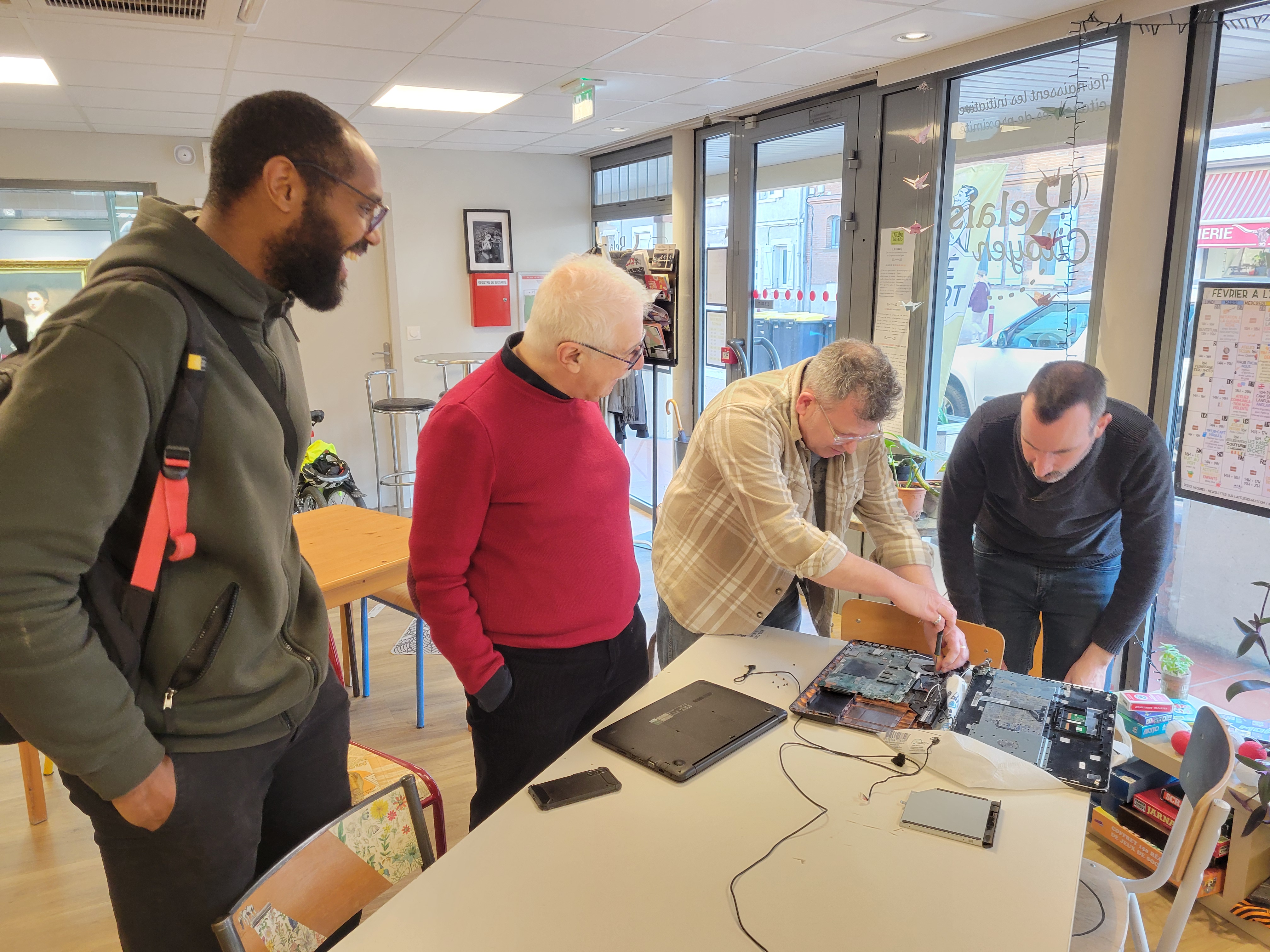 Des bénévoles réunis autour d'un ordinateur portable en cours de réparation